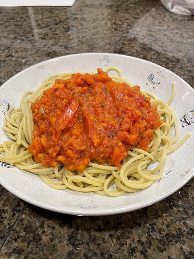 Plate of pasta topped with sauce.