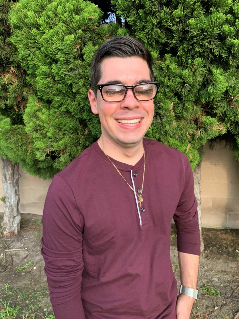 Author Jovany Barba in a burgundy shirt and black glasses.
