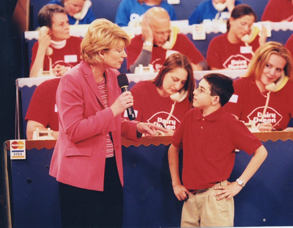 Cole being interviewed by a woman at a telethon.