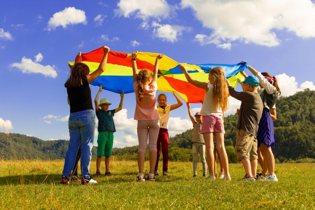 A group of pre teen children playing the parachute game outside in a field. 