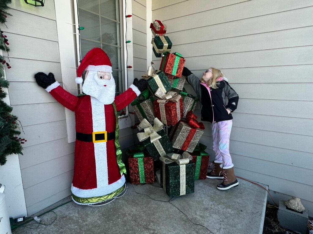 Child exploring an outdoor holiday display of stacked presents 