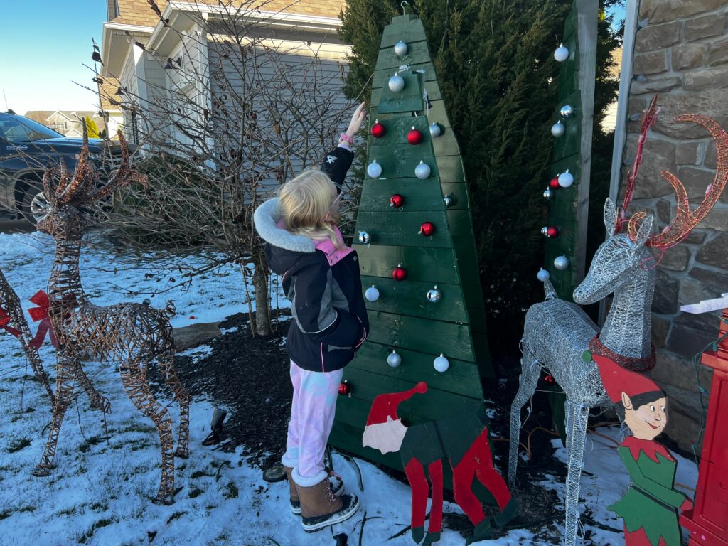child reaching to explore an ornament on an outdoor holiday display 