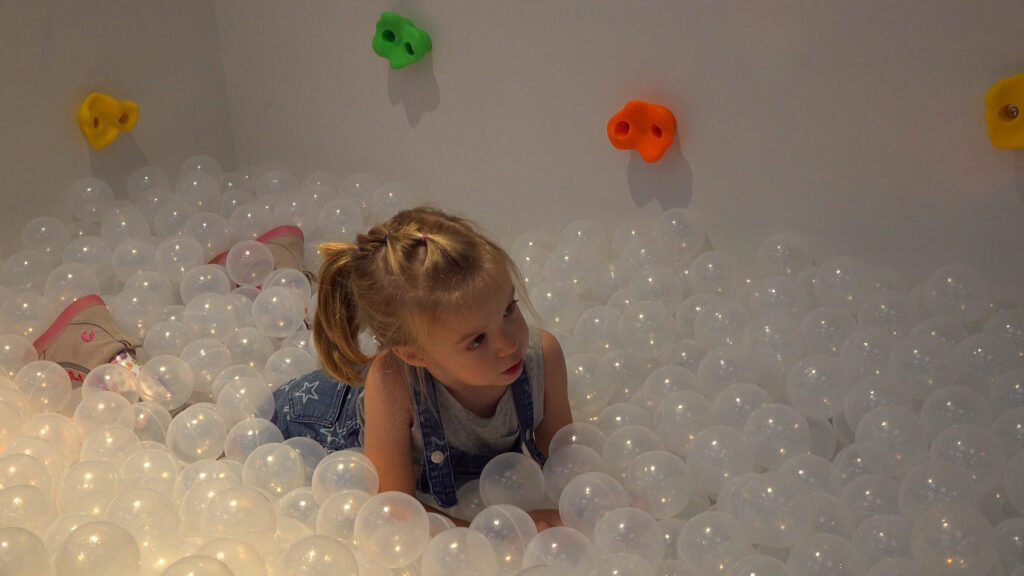 Young girl playing in a ball pit. 
