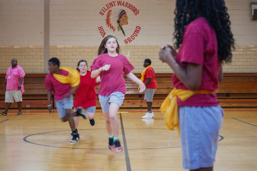 Several middle school age students playing and running in a gymnasium