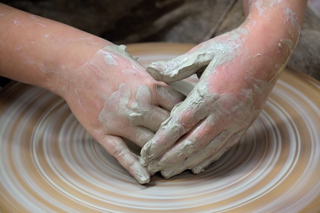 child’s hands on a pottery wheel